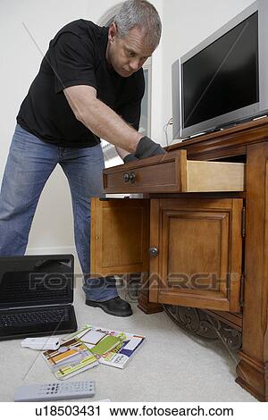 Burglar looking through drawers in house View Large Photo Image Stock Image - Burglar looking through drawers in house. Fotosearch