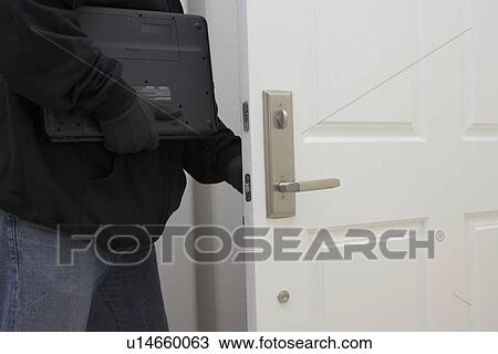 Stock Image - Burglar stealing laptop, mid section. Fotosearch