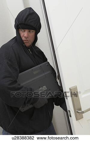 Stock Image - Burglar stealing laptop. Fotosearch