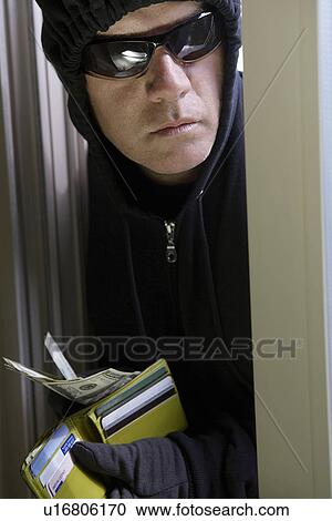 Stock Image - Burglar stealing money, close-up. Fotosearch