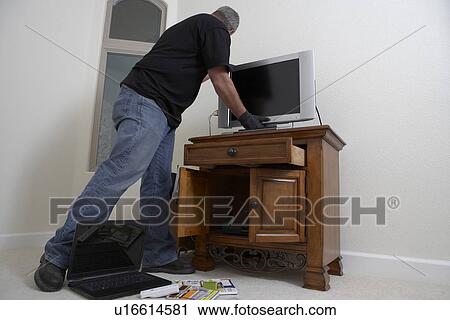 Stock Image - Burglar stealing television from house. Fotosearch