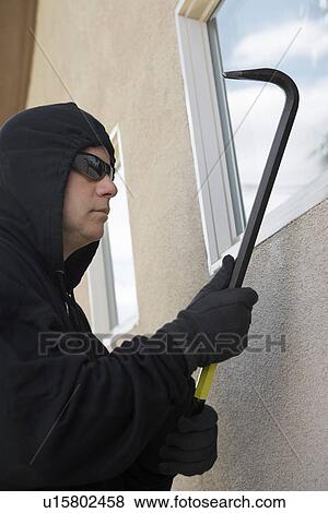 Stock Photo - Burglar using crowbar to break into house. Fotosearch