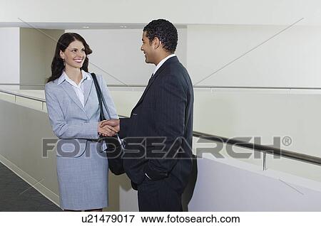 Stock Photo - Business couple shaking hands in office hallway. Fotosearch