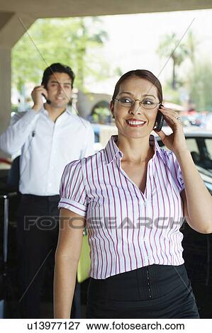 Stock Photo - Business couple using mobile phones outdoors. Fotosearch