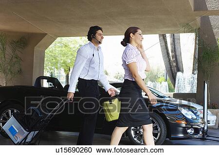 Business couple with luggage passing car View Large Photo Image Stock Image - Business couple with luggage passing car. Fotosearch