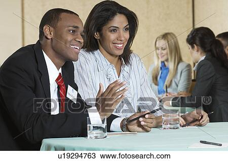 Stock Image - Business man and woman at conference meeting. Fotosearch