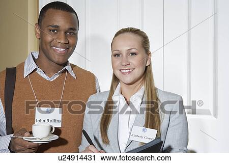 Stock Image - Business man and woman smiling in office, portrait. Fotosearch