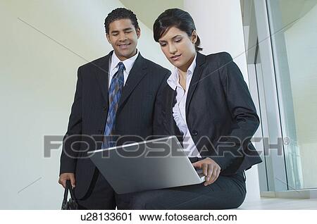 Business man and woman using laptop in hallway, low angle view View Large Photo Image Stock Image - Business man and woman using laptop in hallway, low angle view. Fotosearch