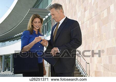 Business man giving card to woman, outdoors View Large Photo Image Stock Image - Business man giving card to woman, outdoors. Fotosearch