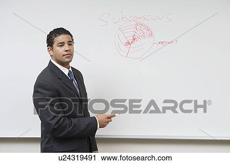 Stock Image - Business man giving presentation standing at whiteboard. Fotosearch