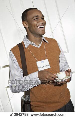 Business man holding cup in office View Large Photo Image Stock Photo - Business man holding cup in office. Fotosearch