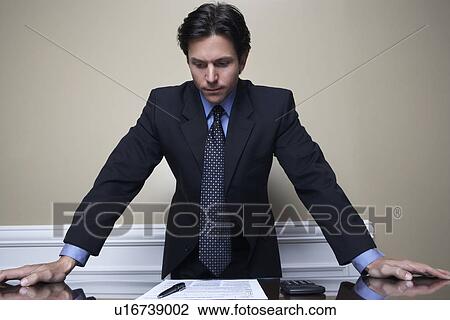 Stock Image - Business man standing at desk in office. Fotosearch