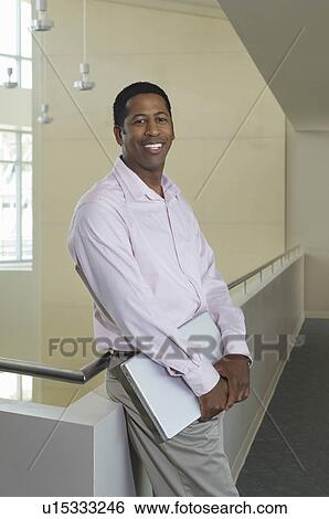 Business man standing by balustrade in office building, portrait View Large Photo Image Stock Photograph - Business man standing by balustrade in office building, portrait. Fotosearch