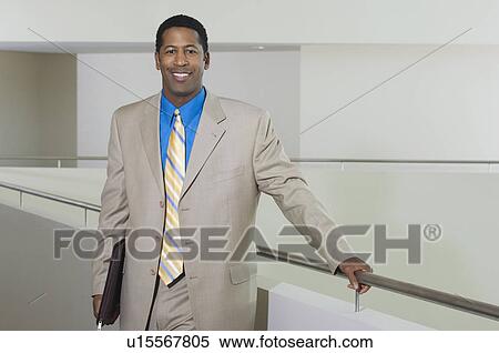 Business man standing by balustrade in office building, portrait View Large Photo Image Stock Photography - Business man standing by balustrade in office building, portrait. Fotosearch