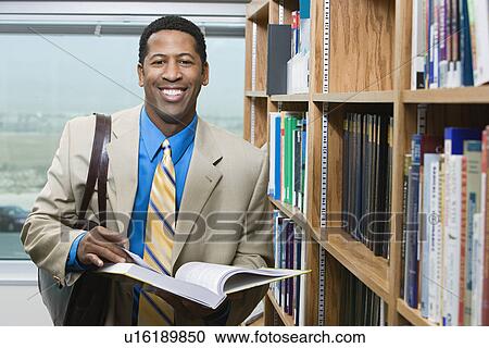 Business man standing by bookshelf, portrait View Large Photo Image Stock Image - Business man standing by bookshelf, portrait. Fotosearch
