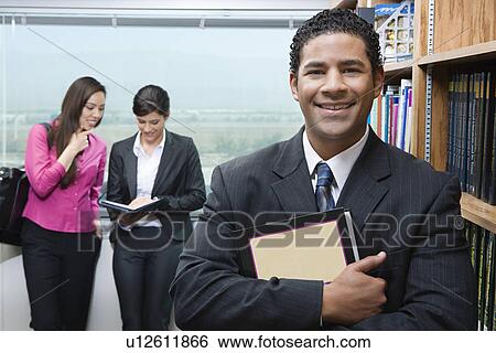 Business man standing near bookshelf in library, portrait View Large Photo Image Stock Photograph - Business man standing near bookshelf in library, portrait. Fotosearch