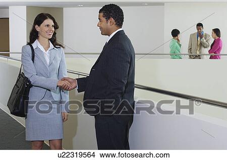Business people shaking hands in office hallway View Large Photo Image Picture - Business people shaking hands in office hallway. Fotosearch
