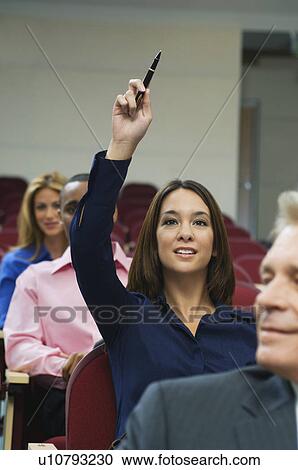 Business people sitting in auditorium, woman rising hand View Large Photo Image Stock Image - Business people sitting in auditorium, woman rising hand. Fotosearch