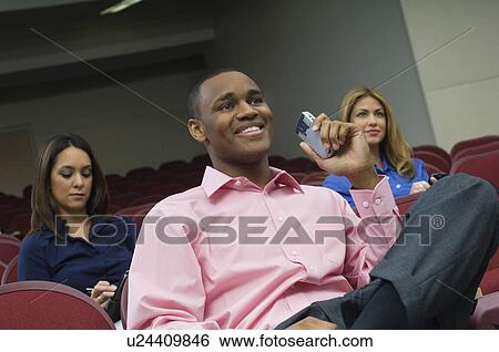 Stock Photograph - Business people sitting in auditorium. Fotosearch