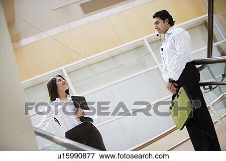 Stock Photo - Business woman and business man talking on stairs. Fotosearch