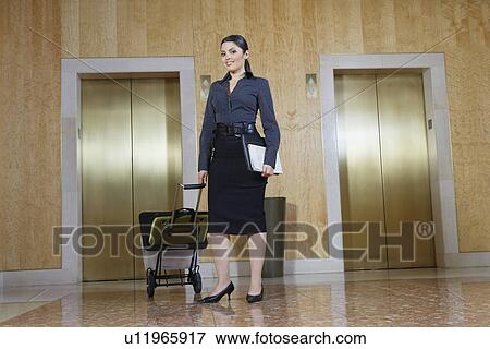 Business woman pulling trolley by elevator View Large Photo Image Stock Photo - Business woman pulling trolley by elevator. Fotosearch