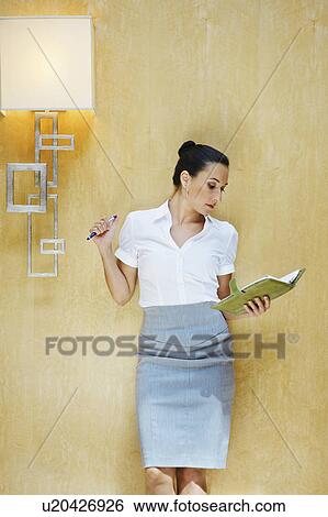 Stock Photograph - Business woman reading document in office. Fotosearch