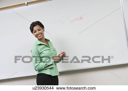 Picture - Business woman standing in front of whiteboard, laughing. Fotosearch