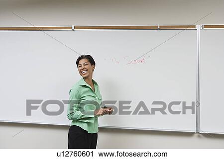 Stock Image - Business woman standing in front of whiteboard, laughing. Fotosearch