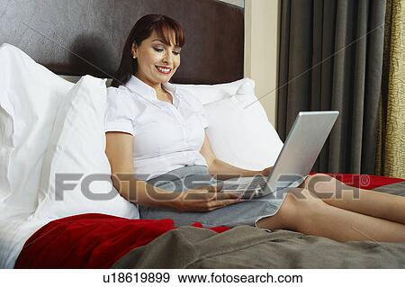 Business woman using laptop on bed View Large Photo Image Stock Photo - Business woman using laptop on bed. Fotosearch