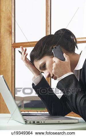 Picture - Business woman using mobile phone at desk in office. Fotosearch