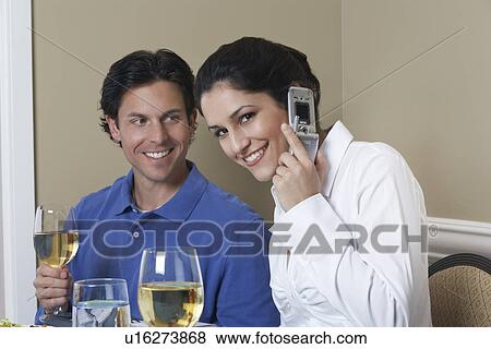 Stock Photo - Business woman using mobile phone beside male colleague in restaurant. Fotosearch