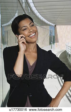 Stock Photograph - Business woman using mobile phone standing outside office building. Fotosearch