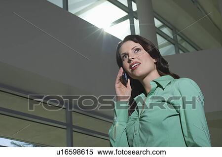 Business woman using mobile phone standing in office building View Large Photo Image Stock Photography - Business woman using mobile phone standing in office building. Fotosearch