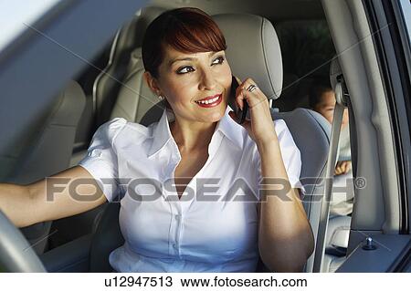 Stock Image - Business woman using mobile phone with son in car. Fotosearch