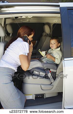 Business woman using mobile phone with son in car View Large Photo Image Stock Photo - Business woman using mobile phone with son in car. Fotosearch