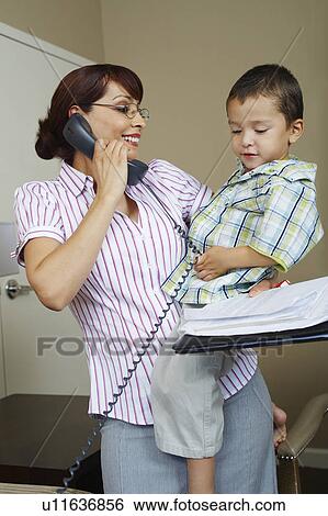 Business woman using phone with son at home View Large Photo Image Stock Photograph - Business woman using phone with son at home. Fotosearch