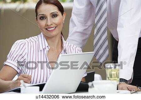 Stock Photograph - Business woman working with colleague, portrait. Fotosearch
