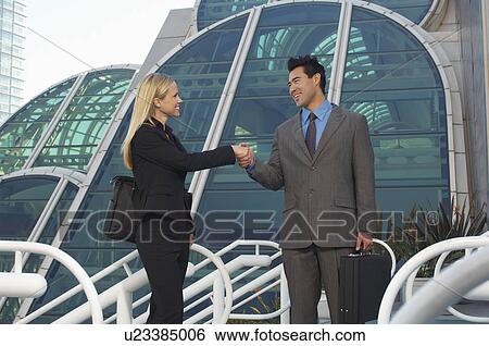 Businessman and woman shaking hands in front of office building View Large Photo Image Stock Photograph - Businessman and woman shaking hands in front of office building. Fotosearch