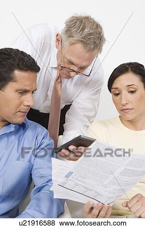 Stock Photo - Businessman Assisting Couple. Fotosearch