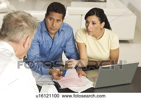 Stock Image - Businessman Assisting Couple with Credit Cards. Fotosearch