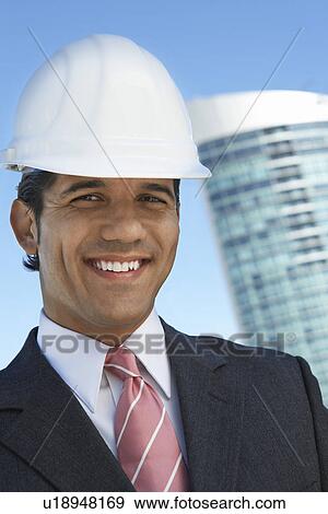 Stock Photo - Businessman in hardhat outdoors, portrait. Fotosearch