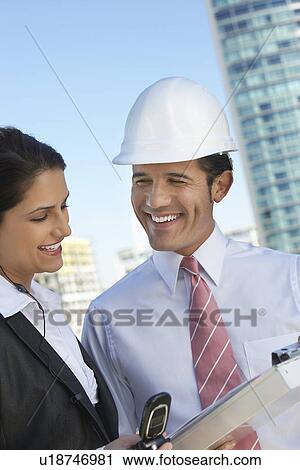 Businessman in hardhat showing clipboard to businesswoman View Large Photo Image Stock Image - Businessman in hardhat showing clipboard to businesswoman. Fotosearch