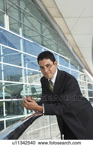 Businessman leaning on railing outside office building View Large Photo Image Stock Image - Businessman leaning on railing outside office building. Fotosearch