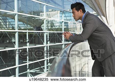 Businessman leaning on railing outside office building View Large Photo Image Stock Photography - Businessman leaning on railing outside office building. Fotosearch