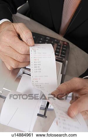 Stock Image - Businessman Looking at Calculator Paper. Fotosearch