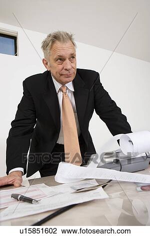 Stock Image - Businessman Looking at Calculator Paper. Fotosearch