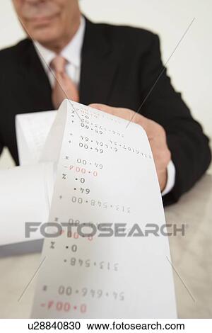 Stock Image - Businessman Looking at Calculator Paper. Fotosearch