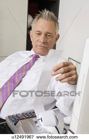 Stock Photo - Businessman Looking at Calculator Paper. Fotosearch