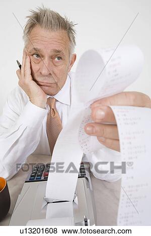 Stock Photo - Businessman Looking at Calculator Paper. Fotosearch