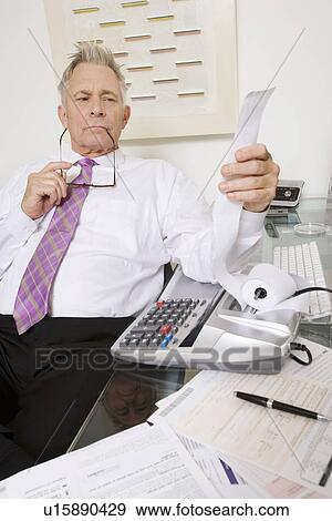 Stock Photo - Businessman Looking at Calculator Paper. Fotosearch